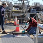 Jake Madden, lab technician with Spinney Creek Shellfish, collects a water sample at the Mystic Wastewater Treatment Plant as Kristin DeRosia-Banick of the state Bureau of Aquaculture looks on.