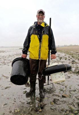 One of the clammers carries his gear to the clamming site at Sasco Hill Beach. Photo: Judy Preston