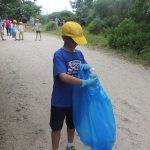 Alex Mynuk deposits an empty water bottle he found off the main trail at Bluff Point into a trash bag.