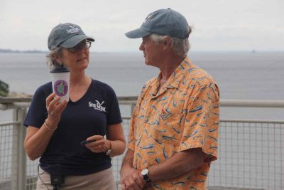 Long Island Sound Outreach Coordinator Judy Preston shows one of the stickers from the campaign to reduce single-use plastic use.