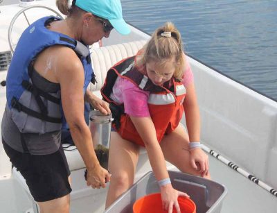 Claudia Koerting, left, academic assistant in marine sciences, takes a sample collected in Little Narragansett Bay from UConn student Mia Dupuis.