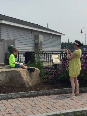 One of the participants in the Downtown New London Waterfront Park Quest poses for his photo next to the statue of playwright Eugene O'Neill as a boy, where some of the clues to the Quest are found.