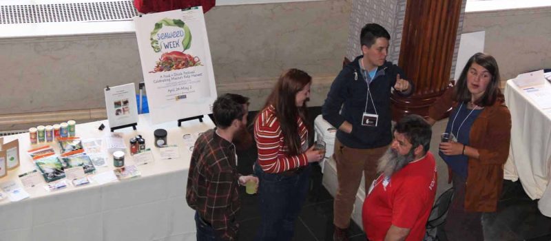 Participants in the National Seaweed Symposium gather near one of the exhibits at the Seaweed Showcase on the second day of the event.