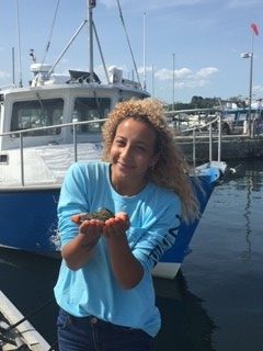 Larissa Tabb holds an oyster on the waterfront at UConn's Avery Point campus in Groton, where she is an undergraduate student studying marine biology.