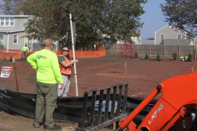 Kristin Walker of the NRCS holds a surveyor’s leveling rod as crews from All Habitat Services of Branford plant bayberry, northern white cedar, red oak and other native species at one of the former home sites.