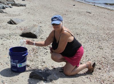 Volunteer Marilyn Miller of Bridgeport places a broken plastic cup in the trash bucket during the cleanup.