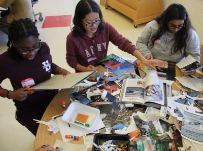 Three members of one of the collage making workshop groups work with recycled materials for their creations.