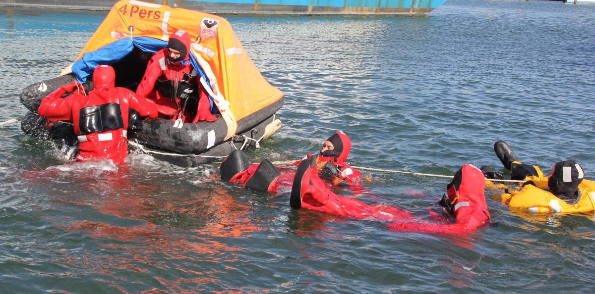 Participants in Safety at Sea training practice boarding a life raft.
