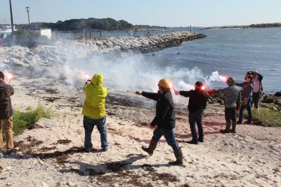 Fishermen and state agency marine agency staff deploy emergency flares on the beach at UConn Avery Point.