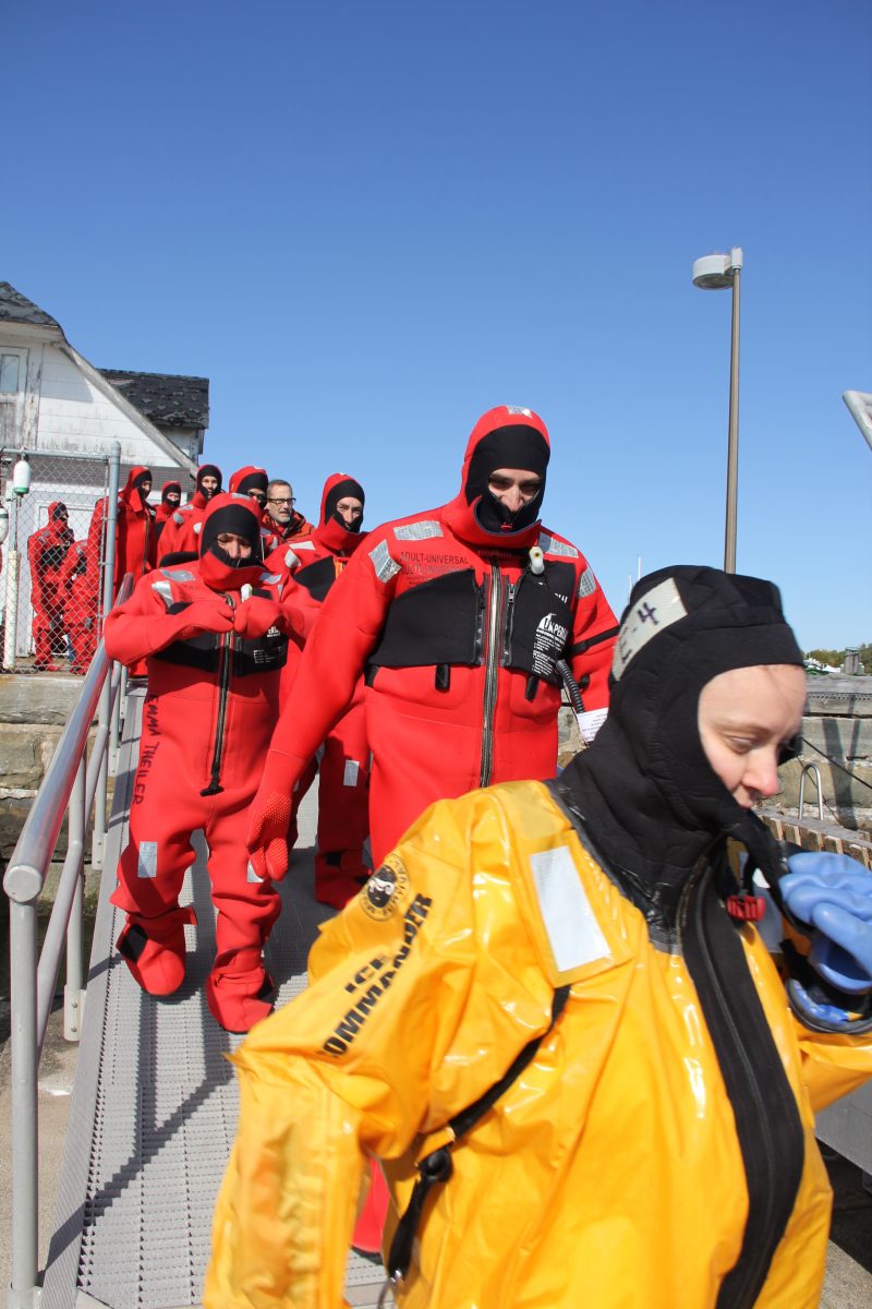 Some of the 49 participants head down the dock to practice getting in the water and maneuvering in their immersion suits.
