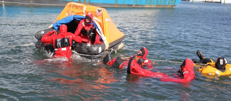 Fishermen in immersion suits practice getting into a life raft during Safety and Survival training in October 2022.