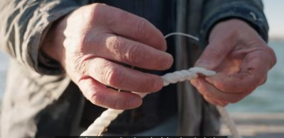 Kelp farmer DJ King feeds seed string onto a line to deploy in Long Island Sound.