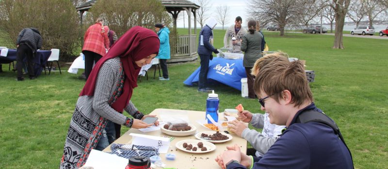 Members of the Avery Point EcoHusky Club, bottom right, make seed bombs for a fellow student at the campus Earth Day festival on April 19. Behind them CT Sea Grant staff share information about shell recycling.