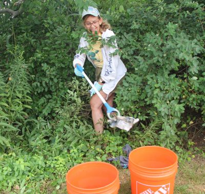 Kathy Bruni of Clinton reached into the bushes to remove trash at the cleanup.
